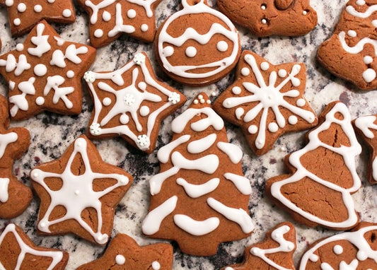 Star, tree, and ornament-shaped gingerbread cookies decorated with white icing on marble
