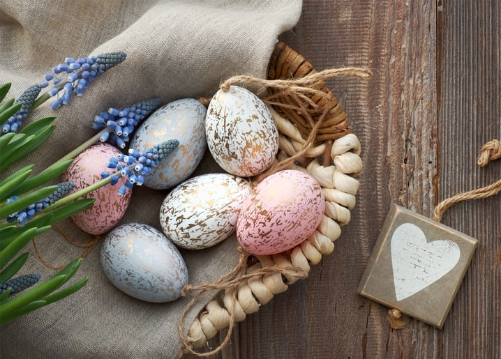 Grey, white and pink crackle-gold eggs in a heart-shaped basket with grape hyacinths and a wooden heart tag
