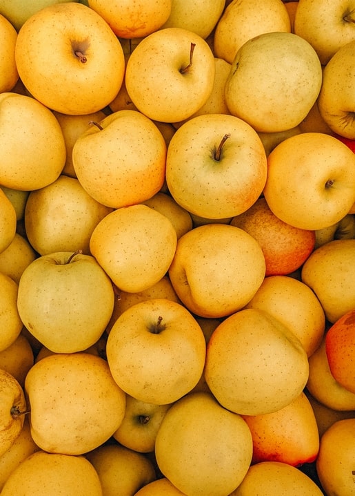 Haufen goldener Äpfel mit einigen roten Früchten, herbstliche Erntefotografie