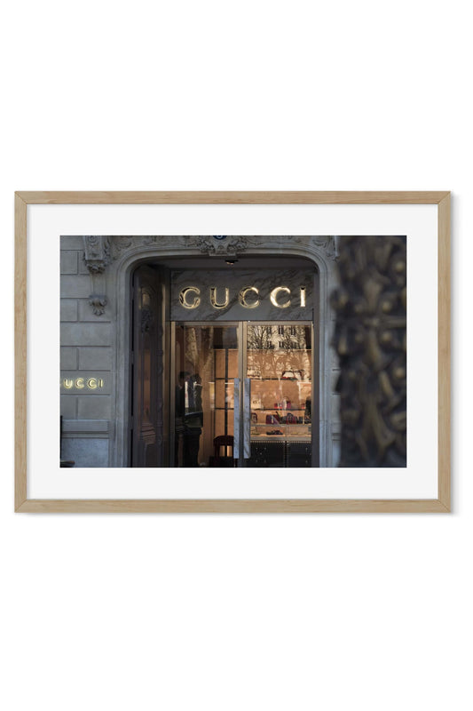 Golden shop sign glowing above a dark marble boutique entrance at dusk