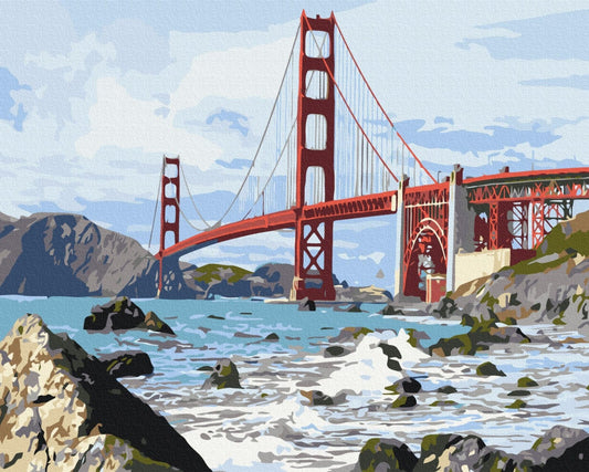 Golden Gate Bridge rising above rocky, wave-battered coastline