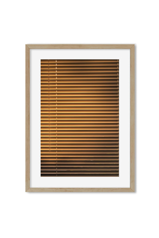 Framed poster showing warm golden light streaming through venetian window blinds
