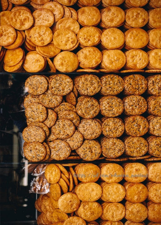 Reihen goldener runder Kekse gestapelt auf den Regalen eines Marktstands