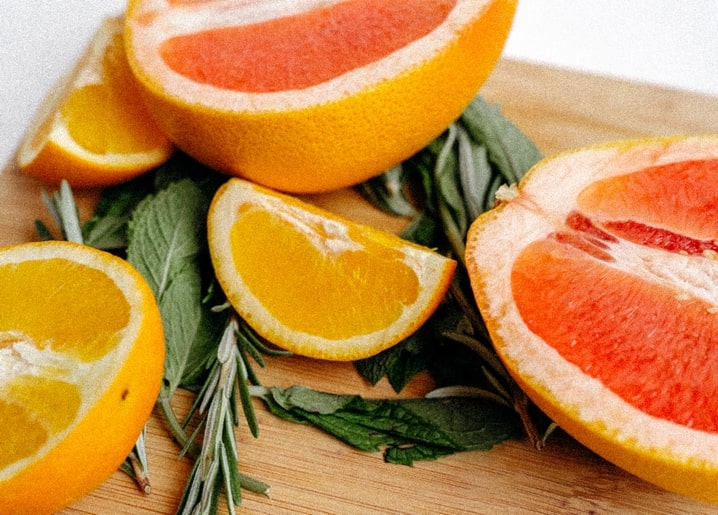 Sliced grapefruit and orange with fresh mint and rosemary on a wooden board