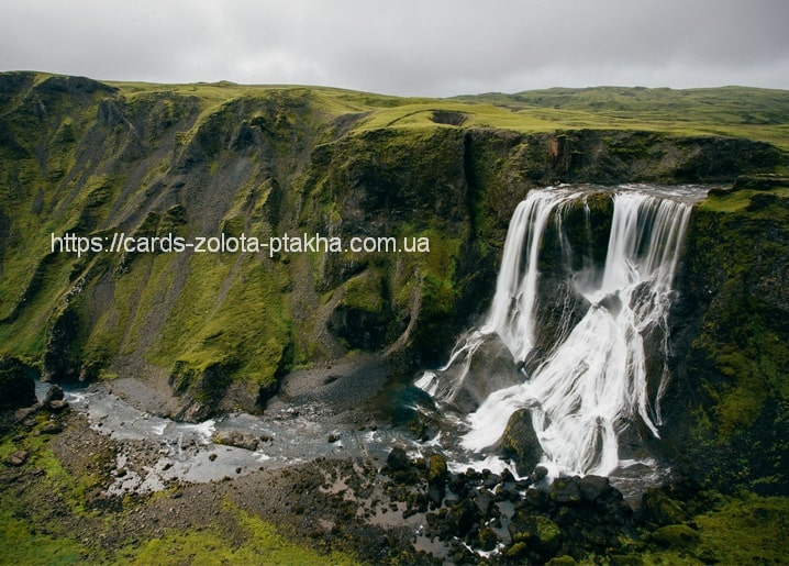 Wasserfall mit mehreren Strömen über einem moosbewachsenen grünen Canyon unter bewölktem Himmel
