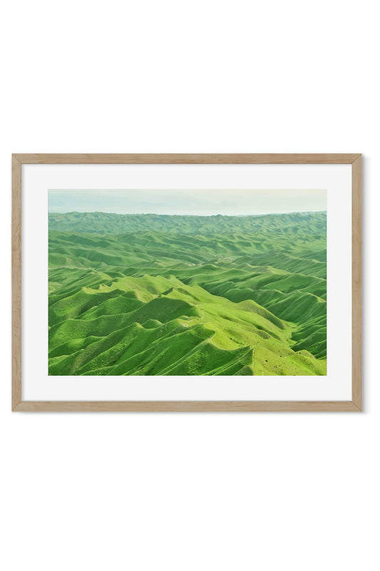 Aerial poster of rolling green hills folded under soft hazy light