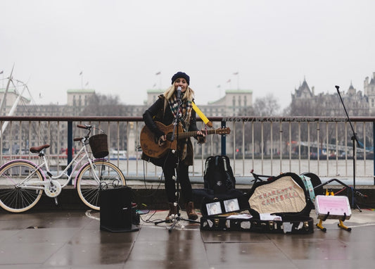 Straßenmusikerin singt mit Gitarre an der Themse in London