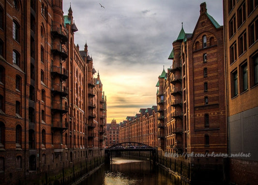 Rote Speicherstadt-Lagerhäuser mit grünen Turmspitzen entlang eines Kanals in Hamburg bei Dämmerung