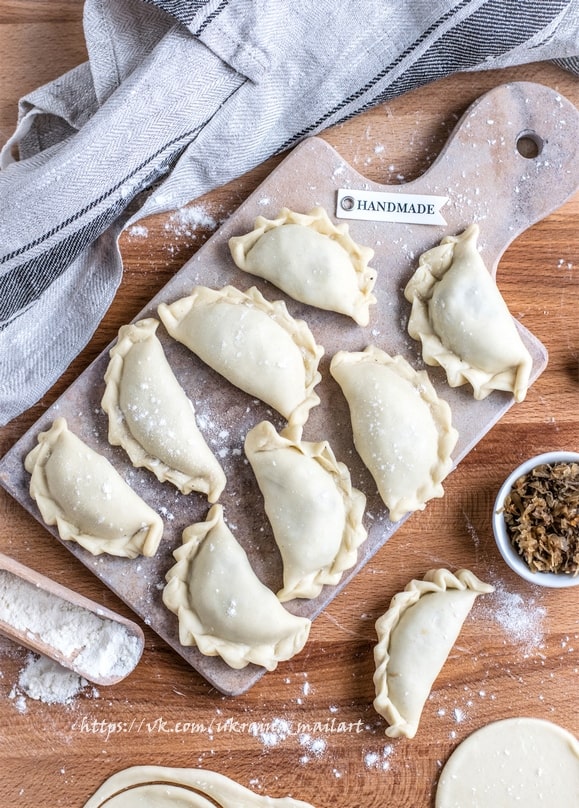 Виліплені вручну вареники на присипаній борошном дошці з биркою Handmade