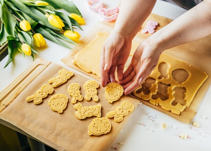 Руки ліплять печиво у формі зайчиків і курчат поруч із тюльпанами