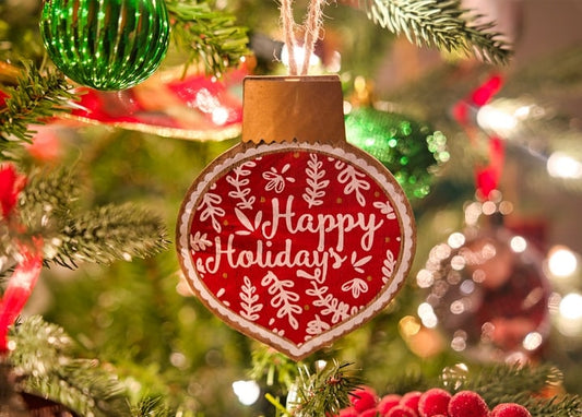 Wooden ‘Happy Holidays’ ornament with folk florals hanging on a Christmas tree
