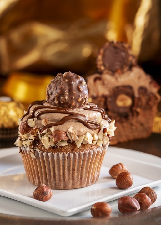 A hazelnut praline cupcake topped with chocolate ganache and a whole hazelnut