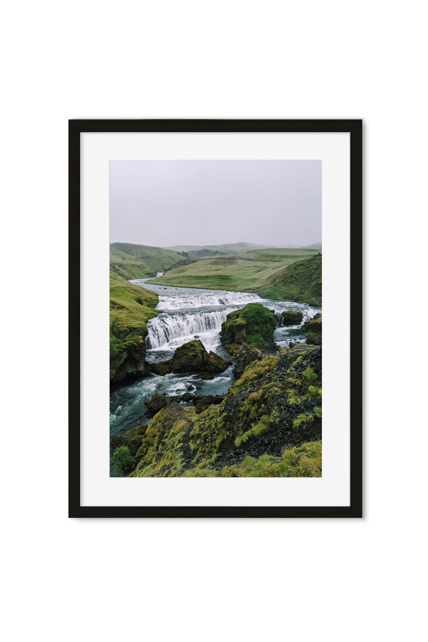 Waterfall cascading through a misty green highland valley
