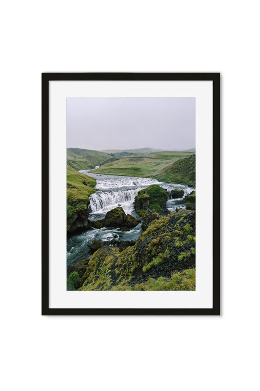 Waterfall cascading through a misty green highland valley