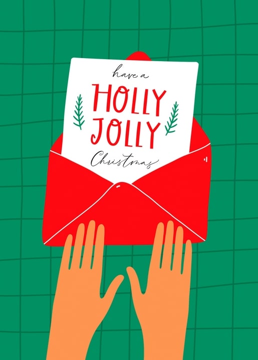 Two hands pulling a Holly Jolly Christmas card from a red envelope on green plaid