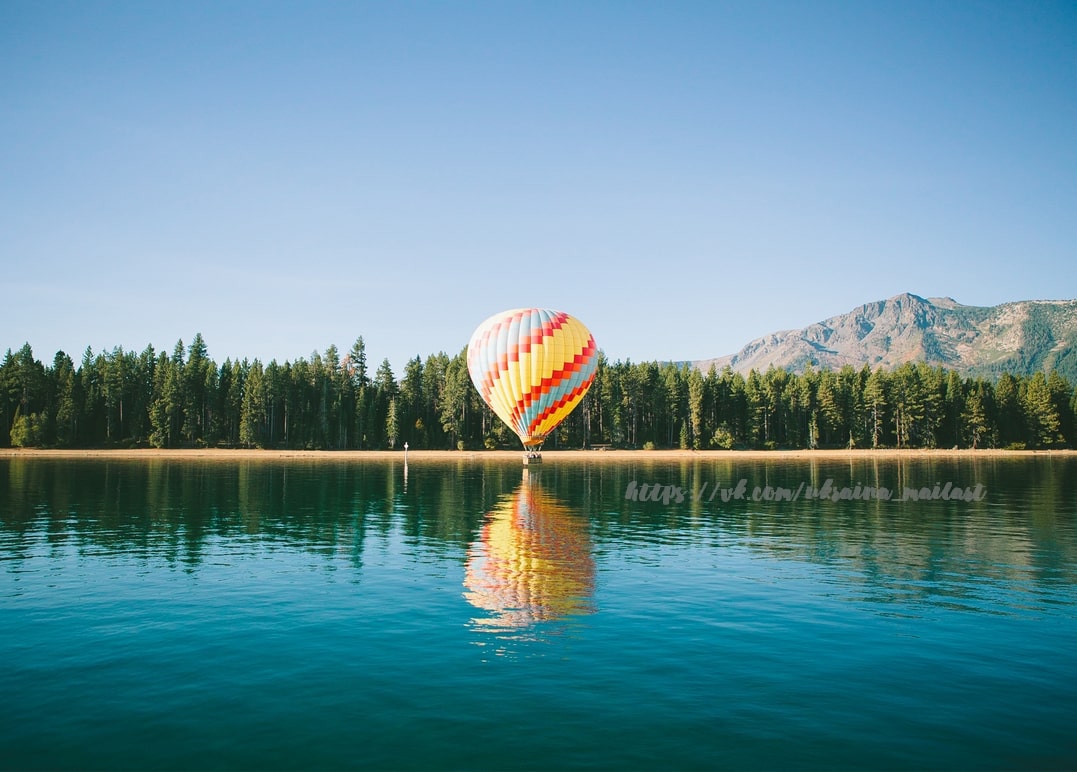 Colorful hot air balloon reflected on a still forest lake