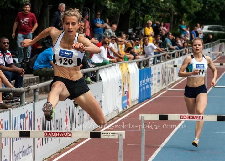 Спортсменка стрибає через бар'єр на легкоатлетичному стадіоні