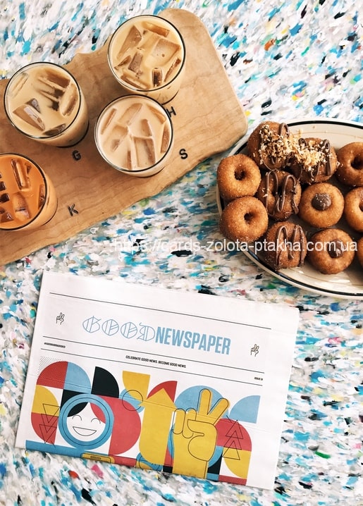 Vier Eiskaffees, ein Teller glasierter Donuts und eine bunte Zeitungs-Attrappe auf dem Tisch.