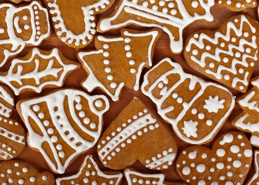 Close-up of frosted gingerbread cookies in heart, tree, bell and mitten shapes on a wooden board