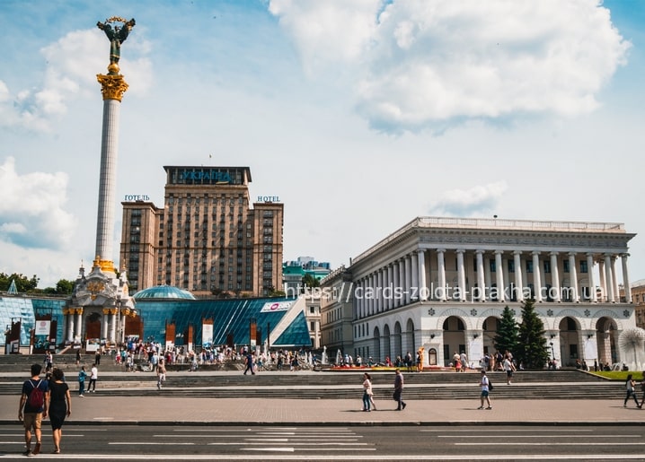 Independence Square in Kyiv with the golden Maidan column, Hotel Ukraina, and pedestrians on a sunny day