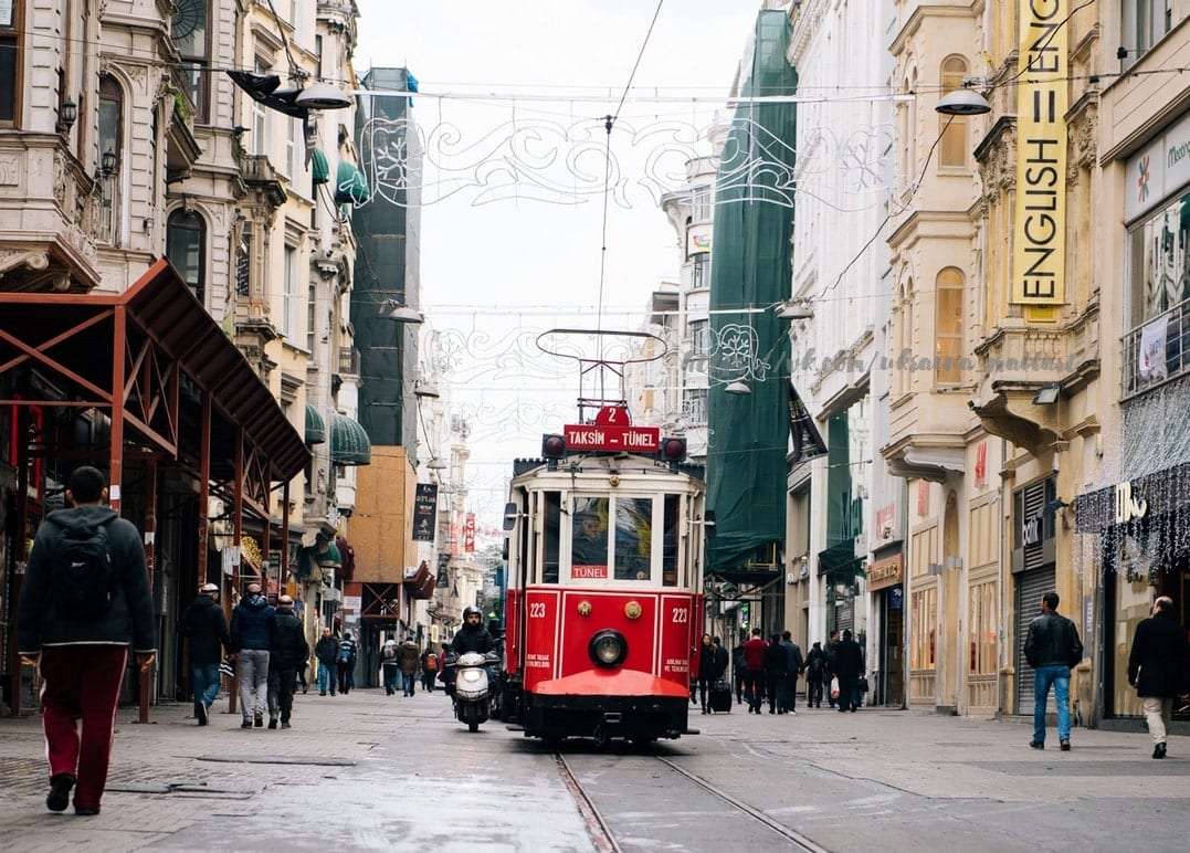 Eine rote historische Straßenbahn fährt die Fußgängerzone Istiklal-Straße in Istanbul entlang