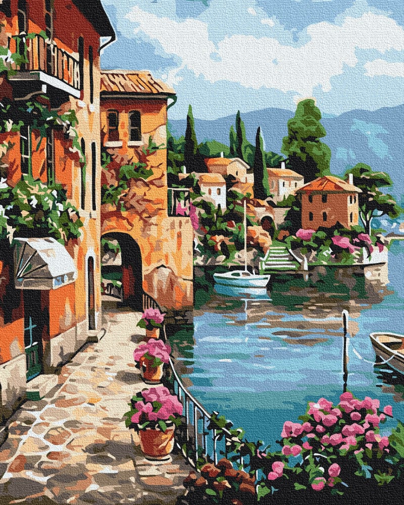 Sun-drenched Italian harbor town with pink geraniums, a stone archway and boats on the water