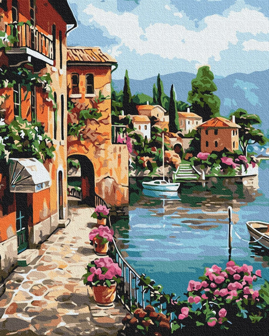 Sun-drenched Italian harbor town with pink geraniums, a stone archway and boats on the water
