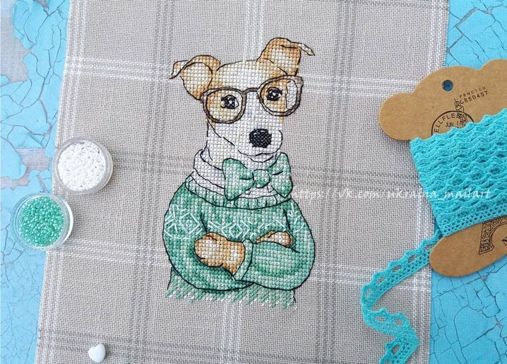 Cross-stitch Jack Russell terrier wearing round glasses, green sweater, and bow tie