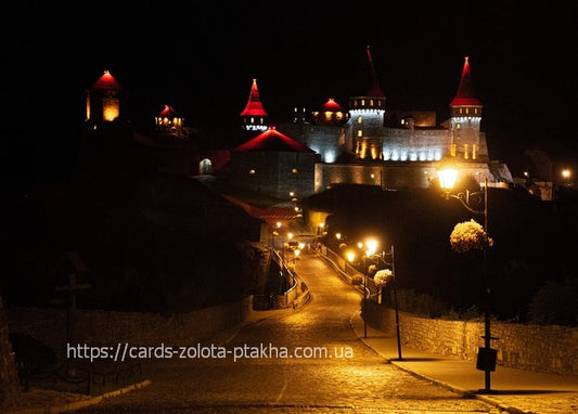 Kamianets-Podilskyi Castle with red-roofed towers illuminated at night