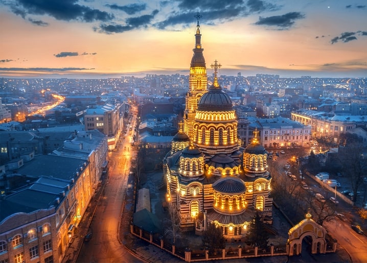 Kharkiv's illuminated cathedral domes glowing at dusk above the city skyline
