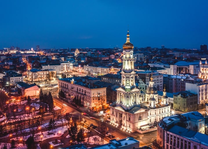 Aerial night view of Kharkiv's illuminated cathedral bell tower and glowing city streets