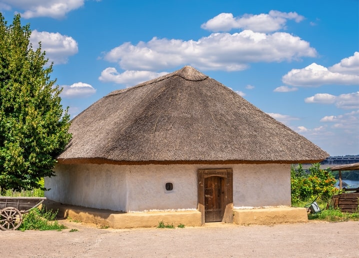 Whitewashed clay cottage with a thatched roof on Khortytsia Island under a blue sky