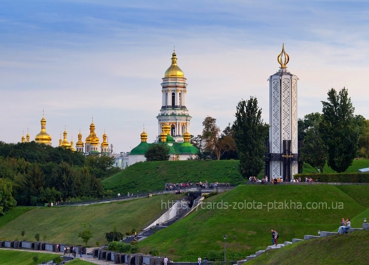 Golden domes and bell tower of Kyiv Pechersk Lavra above a green park at dusk