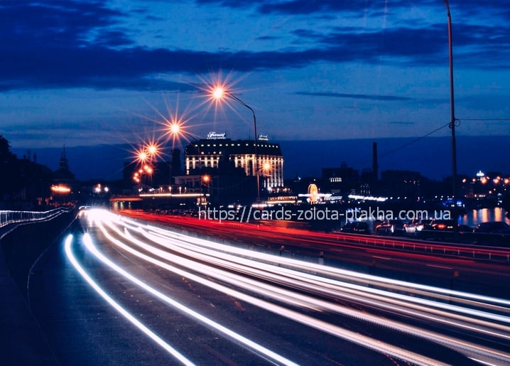 Long-exposure car light trails along the Dnipro embankment in Kyiv at night