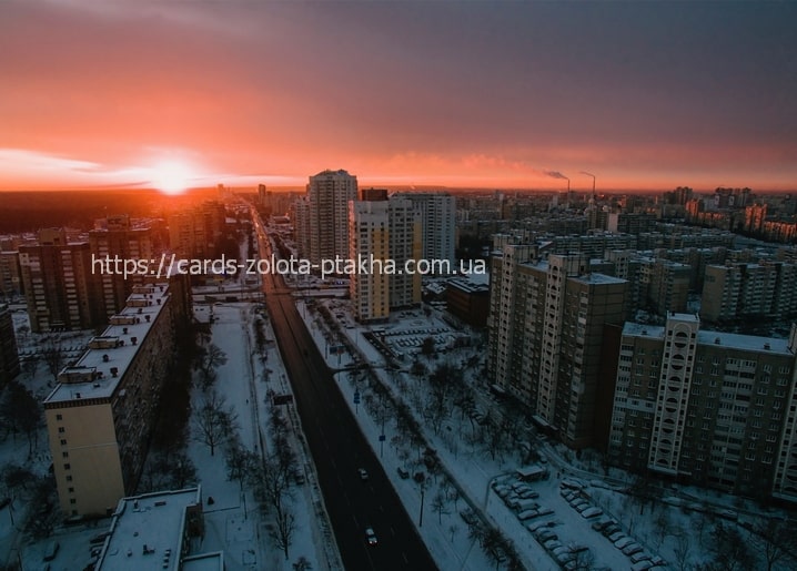 Aerial view of Kyiv apartment rooftops under a crimson winter sunset
