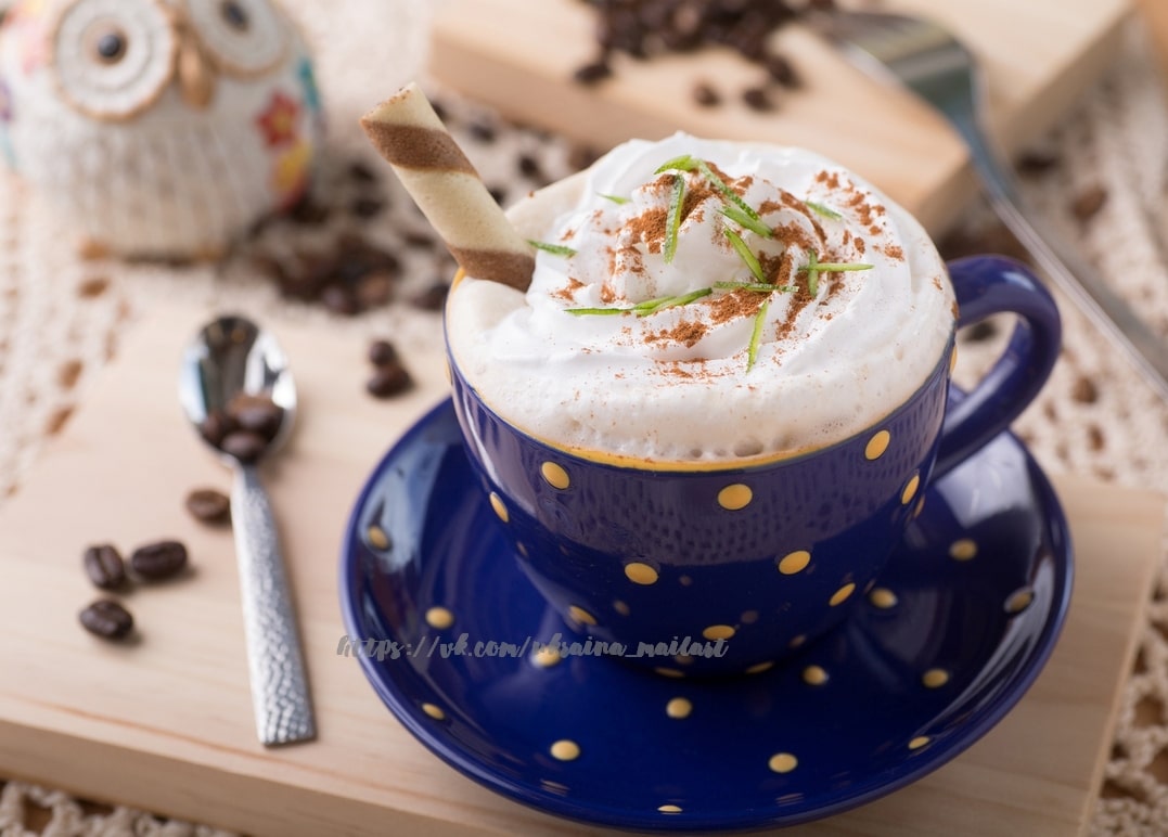 Latte mit Sahnehaube in gepunkteter blauer Tasse mit Keramikeule