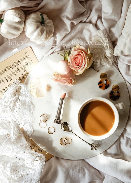 Milchkaffee, rosa Rosen und Schmuck auf einem Marmortablett von oben