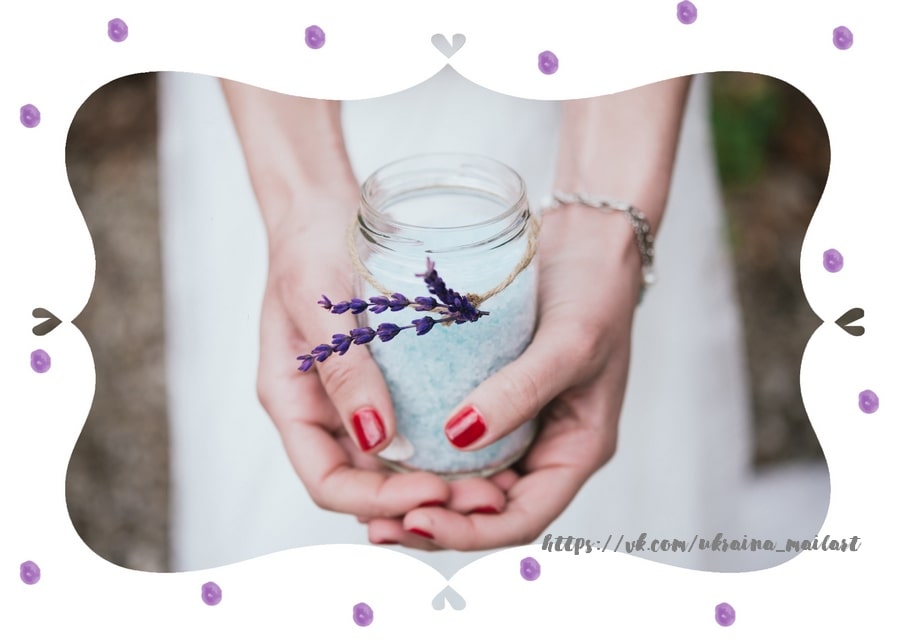 Hands cradling a glass jar of turquoise bath salt tied with twine and lavender