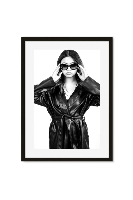 Black-and-white portrait poster of a woman in a leather coat adjusting sunglasses