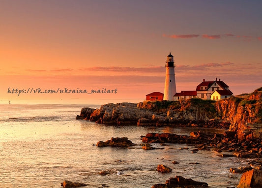 Weißer Leuchtturm und rotes Wärterhäuschen an felsiger Küste zur goldenen Stunde