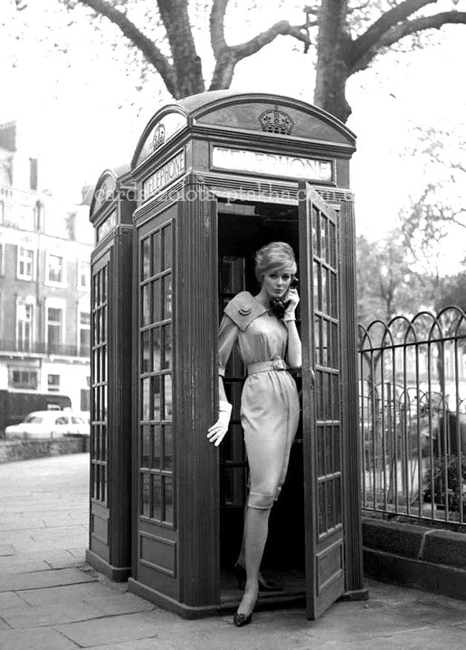 Schwarzweißfoto der 1960er: Frau im goldenen Kleid telefoniert in roter Londoner Telefonzelle