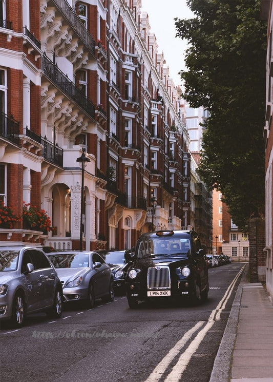 Schwarzes Londoner Taxi fährt durch eine backsteinrote Straße mit parkenden Autos