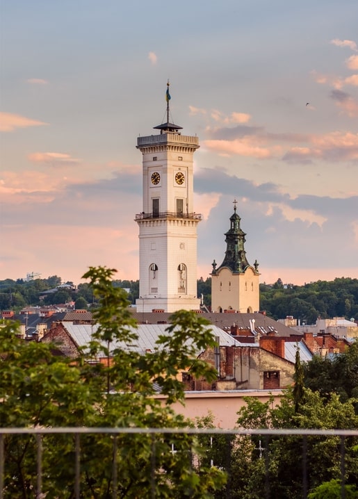 Weißer Rathausturm von Lwiw über den Dächern der Altstadt bei Sonnenuntergang