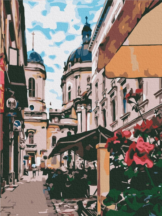 Enge Altstadtgasse in Lemberg mit barocken Kirchenkuppeln, gestreiften Markisen und rosa Blüten.