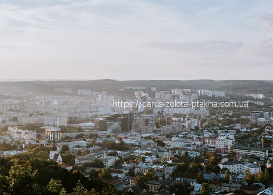 Hazy aerial panorama of Lviv's rooftops and hills at golden hour