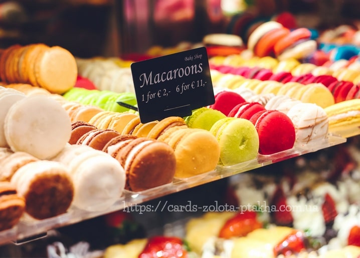 Bunte Macarons in der Konditorei-Vitrine mit handgeschriebenem Preisschild