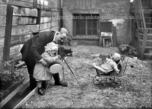 Vintage-Foto eines Mannes, der ein Kleinkind mit einer alten Kamera fotografiert, daneben eine Puppe im Wagen
