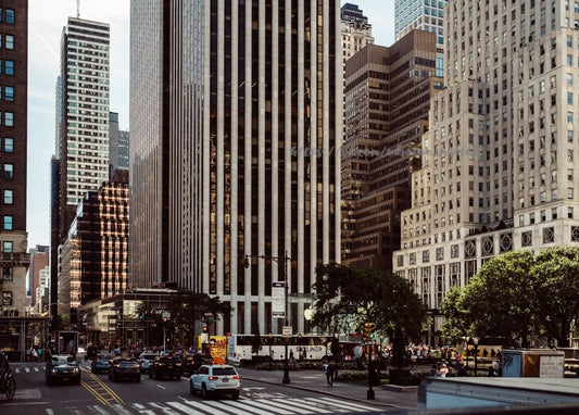 Wolkenkratzer ragen über eine belebte Straße in Manhattan mit Autos und Fußgängern am Zebrastreifen