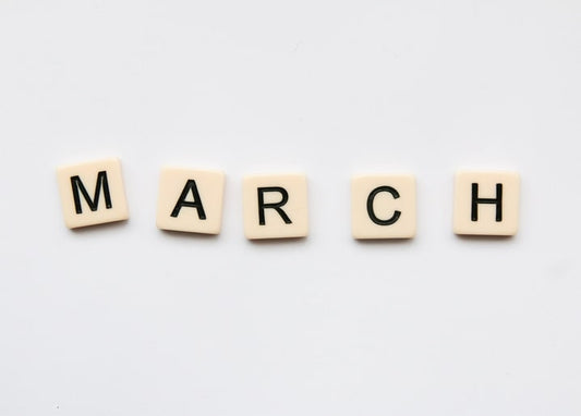 Кремові кубики-літери складають слово MARCH на білому тлі