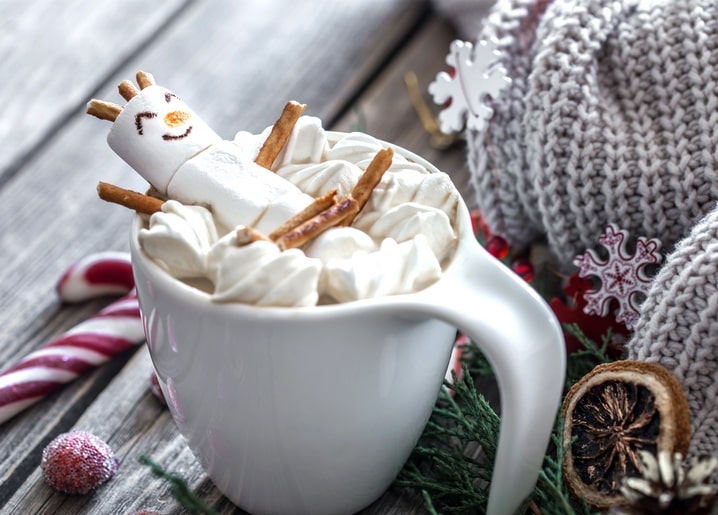Marshmallow-Schneemann liegt auf Baiser und Salzstangen in einer Tasse heißem Kakao